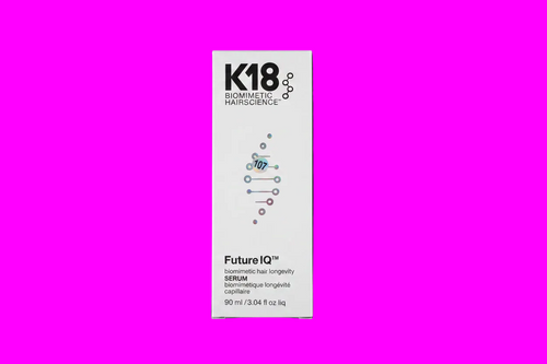 A tall white rectangular box for K18 Biomimetic Hairscience Future IQ Serum, centered on a vivid magenta background. The packaging features black text and a blue and purple DNA helix graphic.